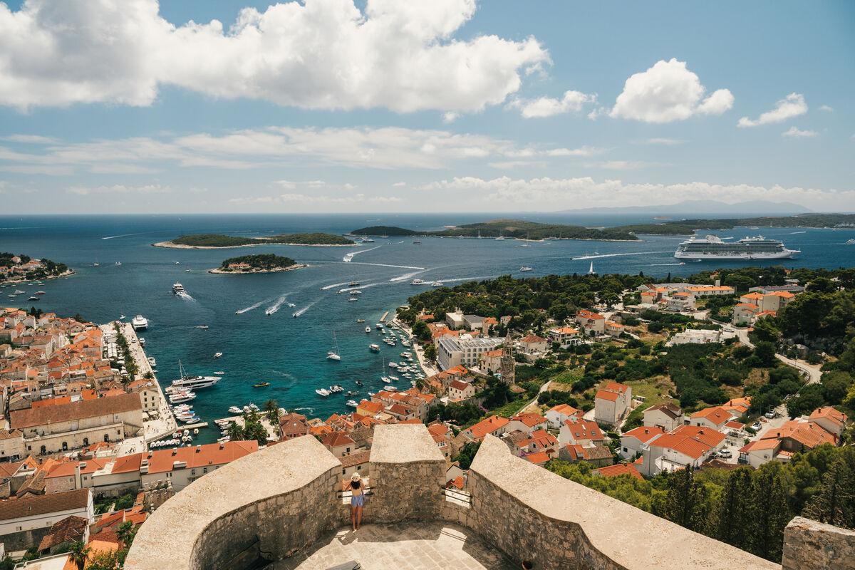 Oceania Vista anchored off a historic Croatian harbor town with red-tile roofs and green islands beyond