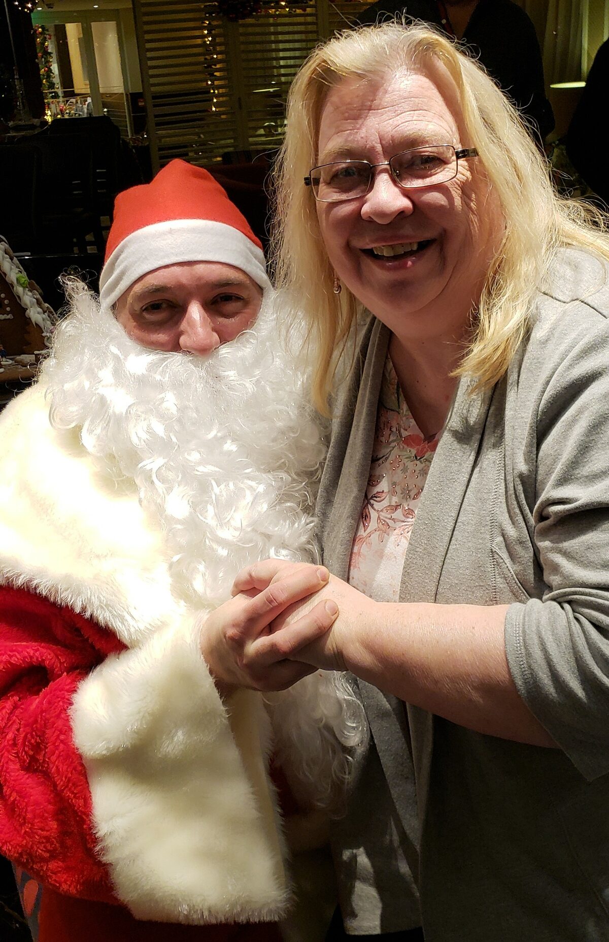 Susan Young smiles beside Santa in AmaStella's festively decorated lounge